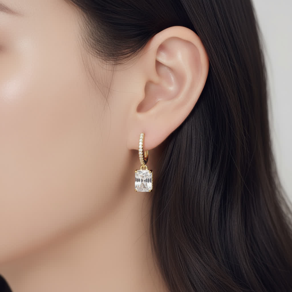 Gold earring with a diamond on an ear against a neutral background