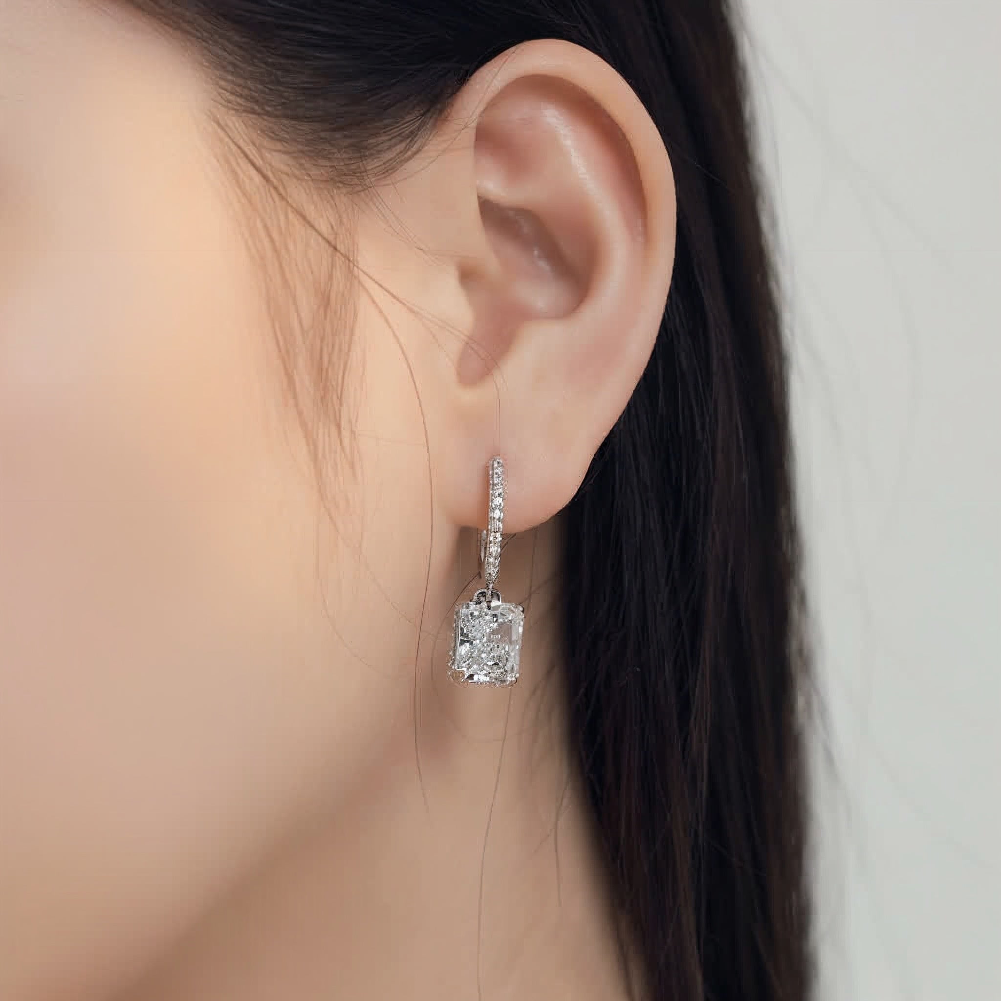 Close-up of a diamond earring worn by a person with a neutral background