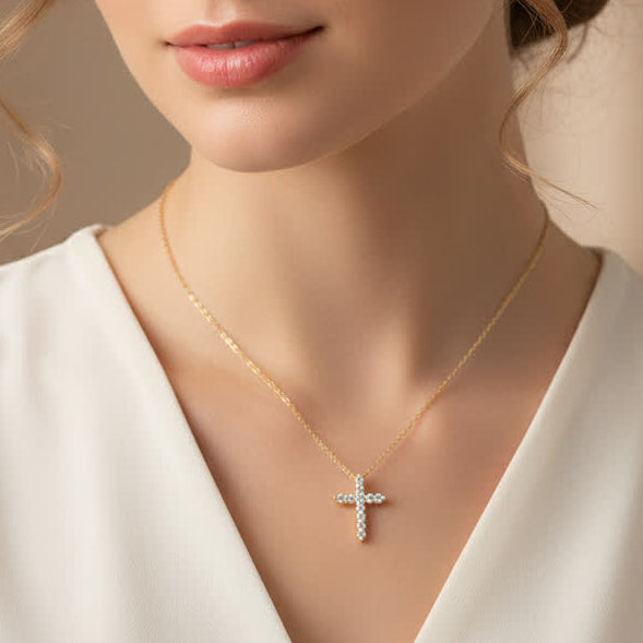 Woman wearing a gold necklace with a cross pendant against a beige background