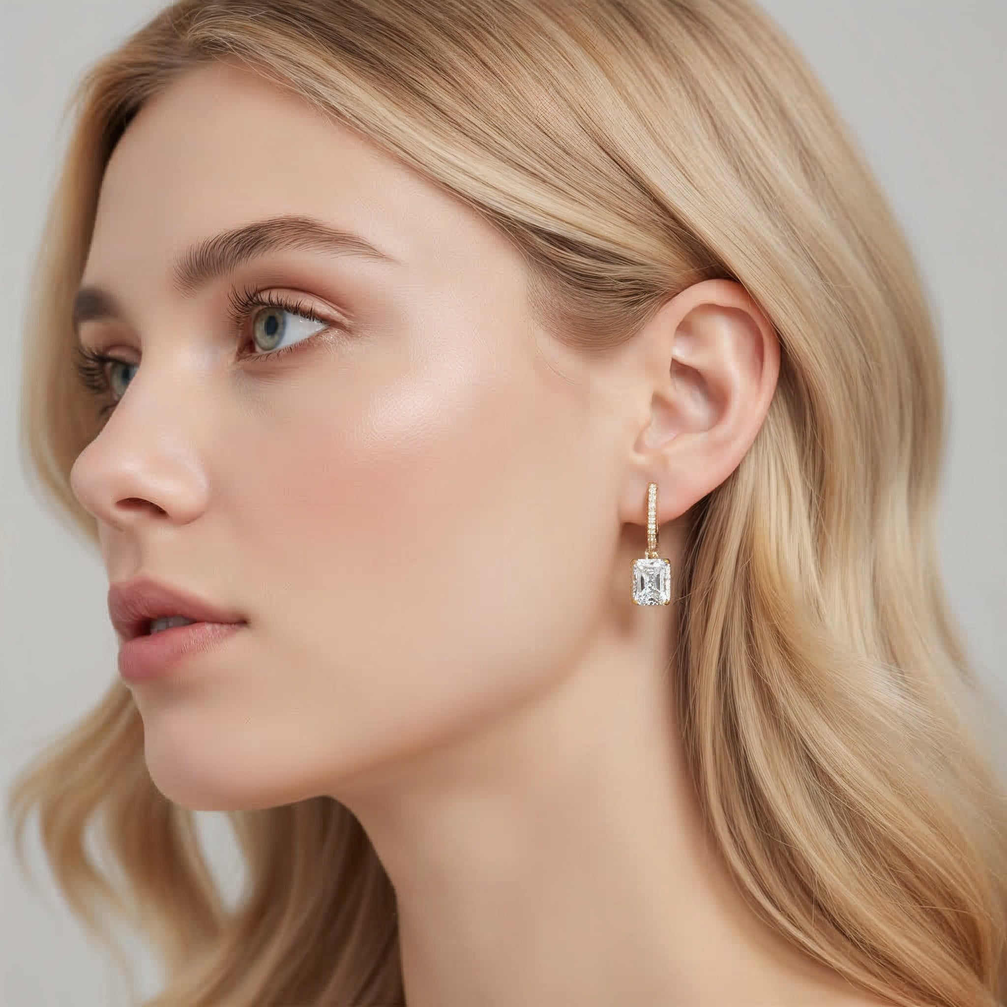 Close-up of a woman wearing diamond earrings with a neutral background
