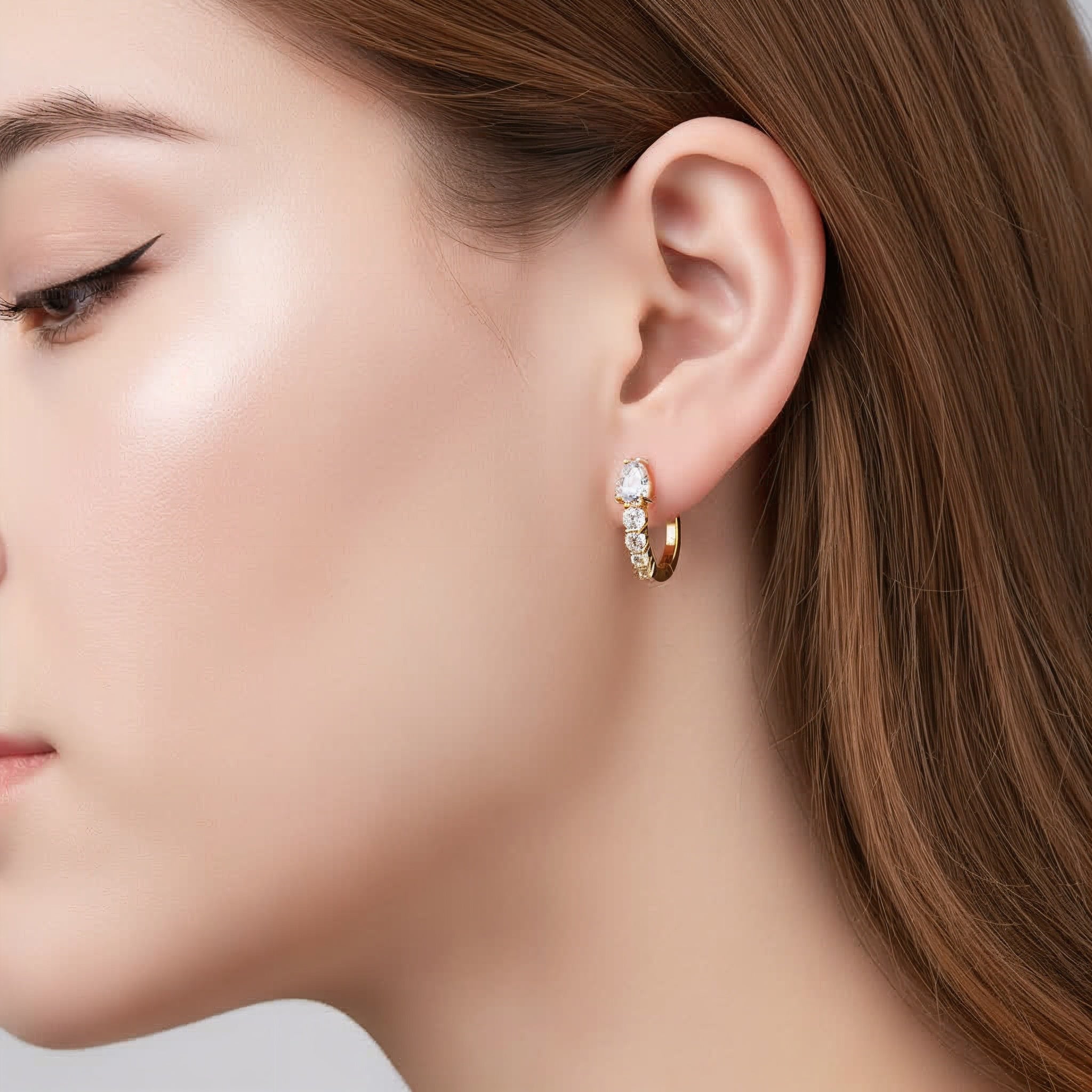 Close-up of a woman wearing a gold hoop earring with small diamonds.
