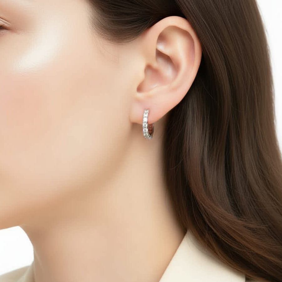 Close-up of a person wearing a silver hoop earring with a blurred background